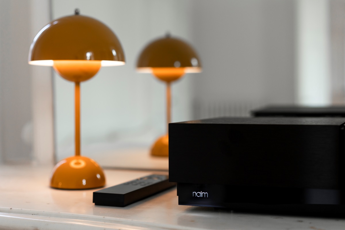 Naim Audio Uniti Nova PE Lifestyle Front of unit with illuminated logo and lamp plus remote control, streaming amplifier from loud and clear glasgow, scotland, uk