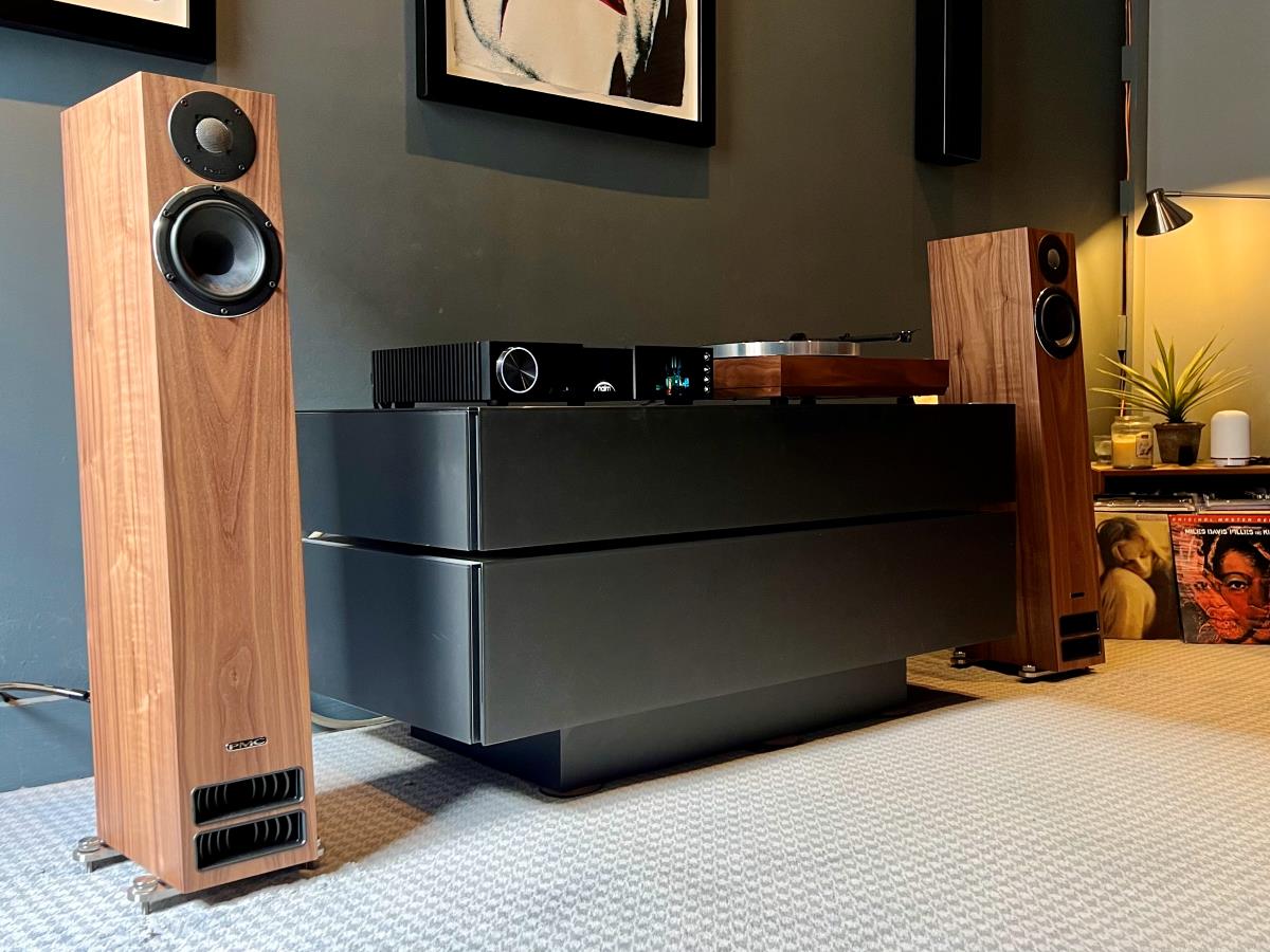 pmc twenty5.23i speakers in oak finish in loud & clear dem room with naim nsc 222 streaming preamplifier and linn sondek lp12 turntable with light in corner and stacks of vinyl