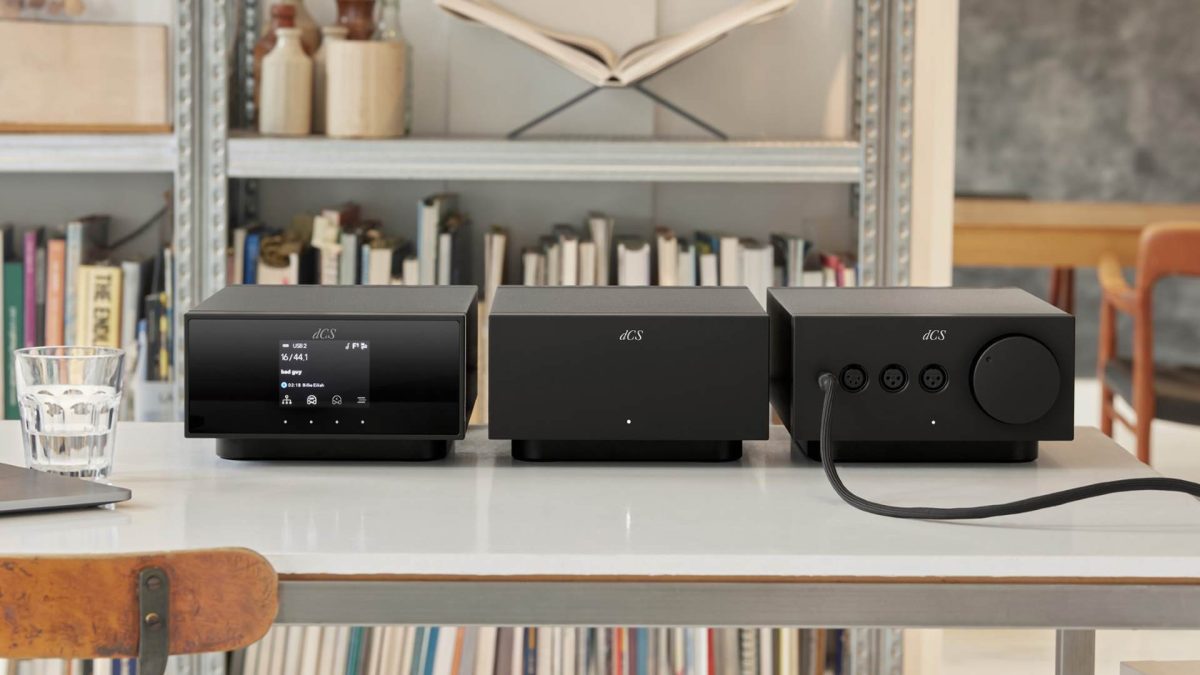 dcs lina headphone system, with network streaming dac, master clock and amplifier on a white table in a room with book shelves