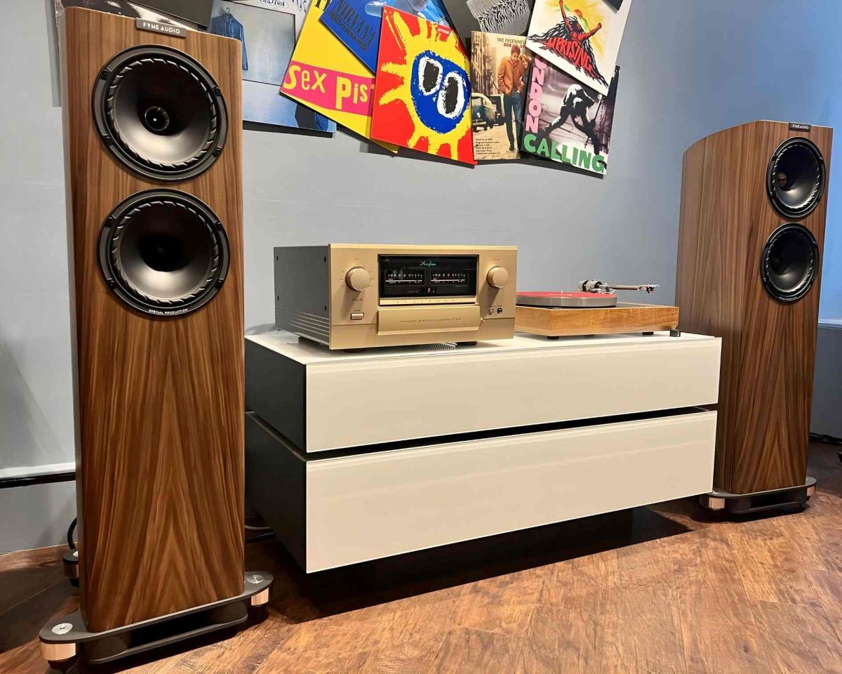 Fyne audio f702sp floorstanding speakers in front shop with accuphase amplifier and linn sondek lp12 turntable on white spectral rack. album artwork as a jumbled collage on wall