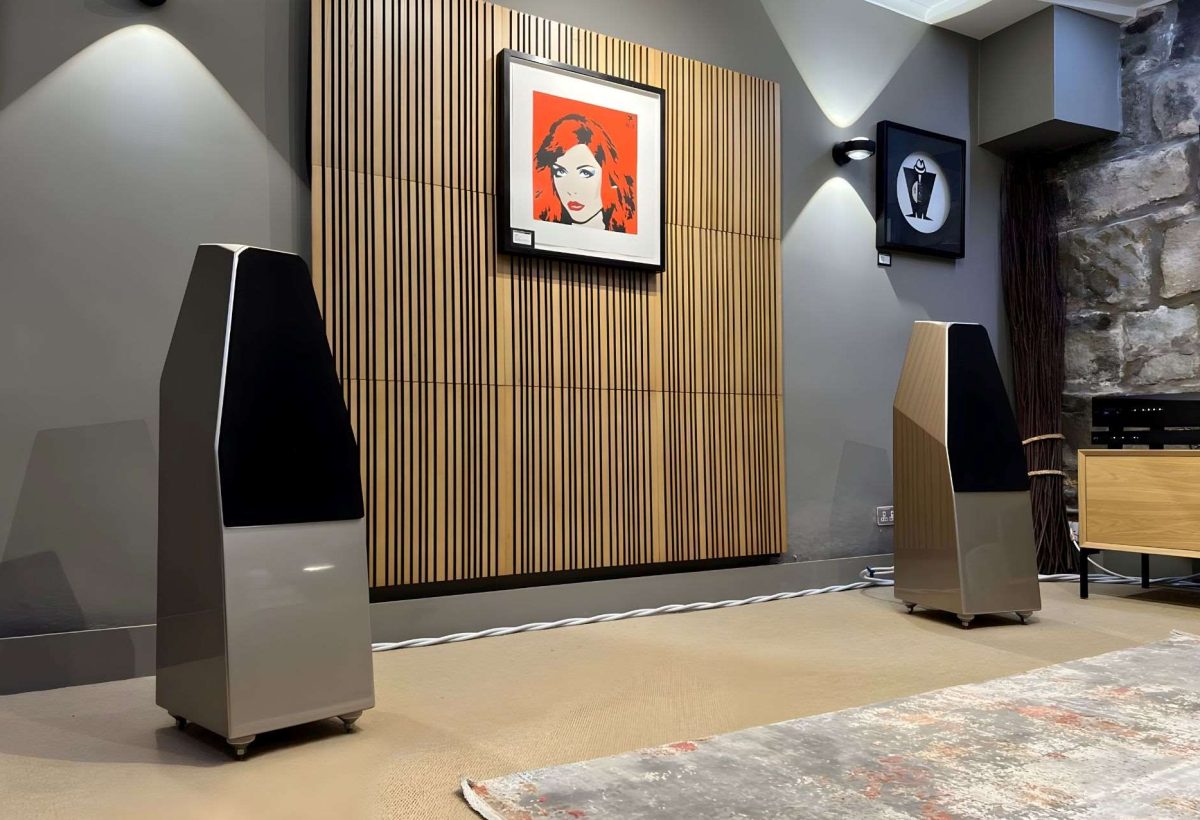 wilson audio sabrinax floorstanding speakers in loud and clear glasgow demonstration room with artnovion acoustic treatment on wall and pop art print of debbie harry, dcs rossini apex dac and clock at side on a clic equipment rack and rug in foreground