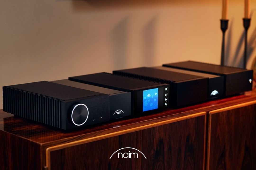 naim classic 200 series stereo system with nsc 222 streaming preamplifier and nap 250 power amplifier, lifestyle image with electronics on dark wooden sideboard and candlestick in background, high-end audio from loud and clear hi-fi, glasgow, scotland, uk