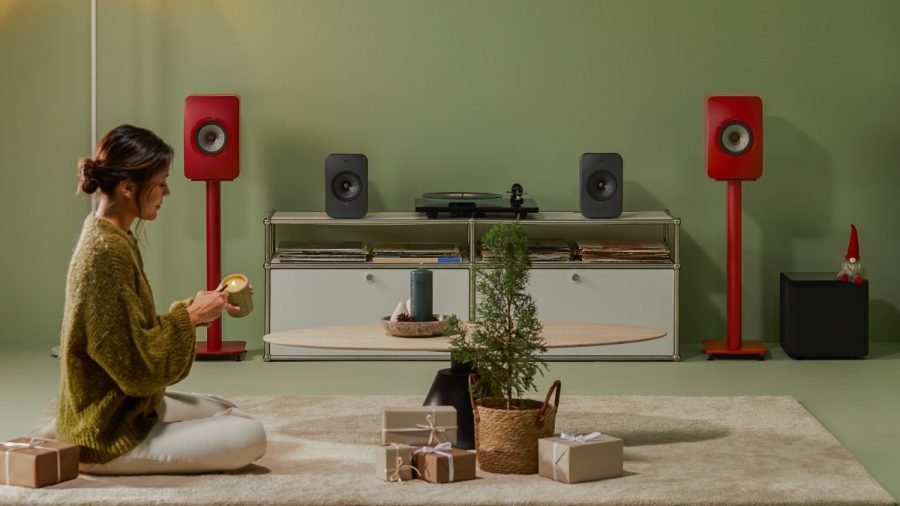 KEF wireless speakers ls50 wireless II on stands and lsx II LT on stand with turntable inbetween, woman sitting on carpet in front lighting a candle with small tree and wrapped presents in front, hi-fi from loud and clear glasgow, scotland, uk